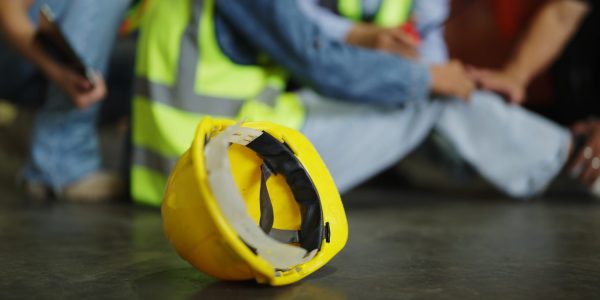 construction hat on ground with injured worker in the background